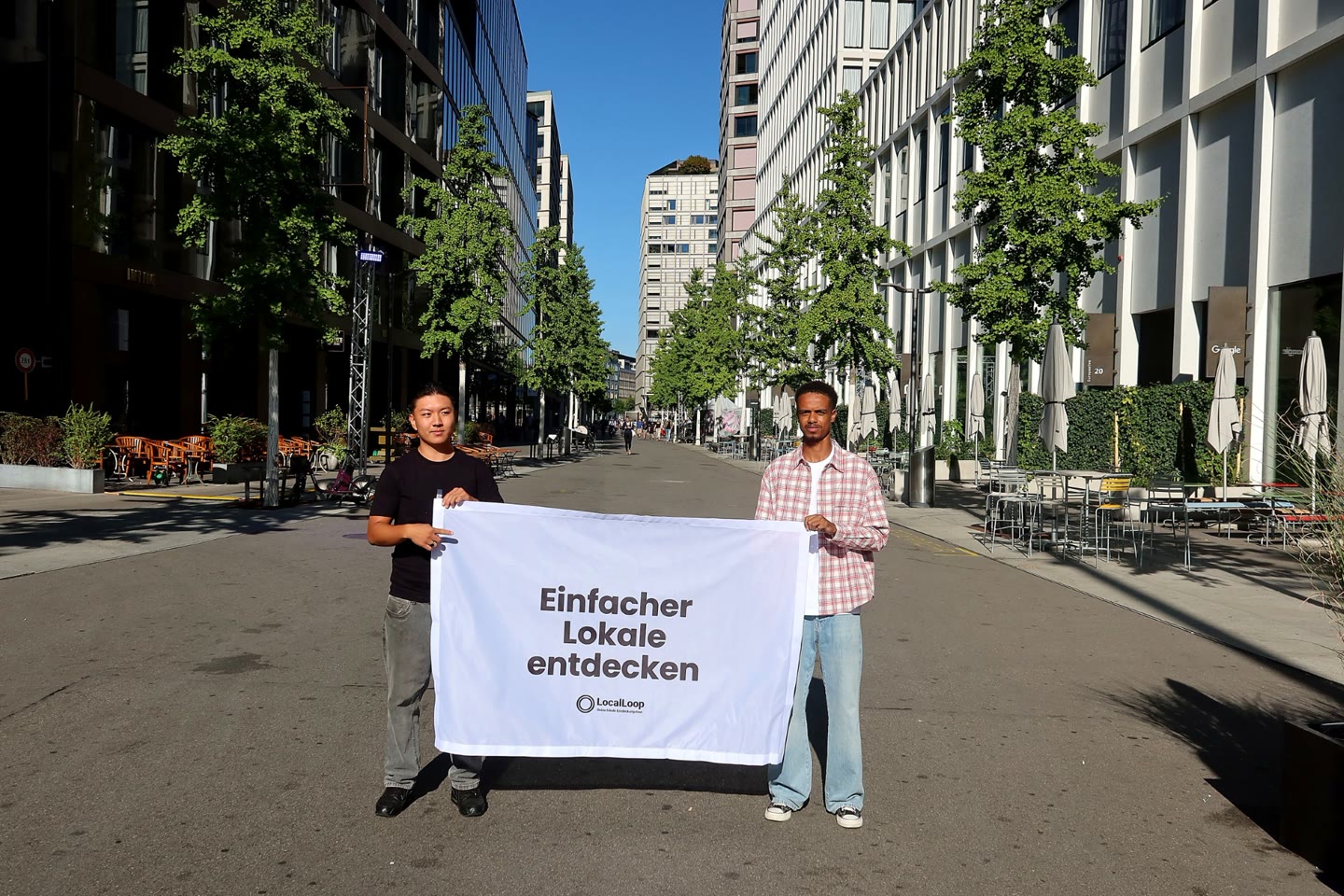 Tenzin Khangsar und Abdirahman Mahamud, Gründer von LocalLoop, mit einem Banner „Einfacher Lokale entdecken“